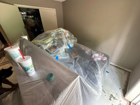 Carpet lifted and tenant furniture covered and protected inside a flood-damaged apartment unit
