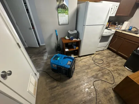Commercial dehumidifier running in a flood-damaged apartment to pull moisture from the air