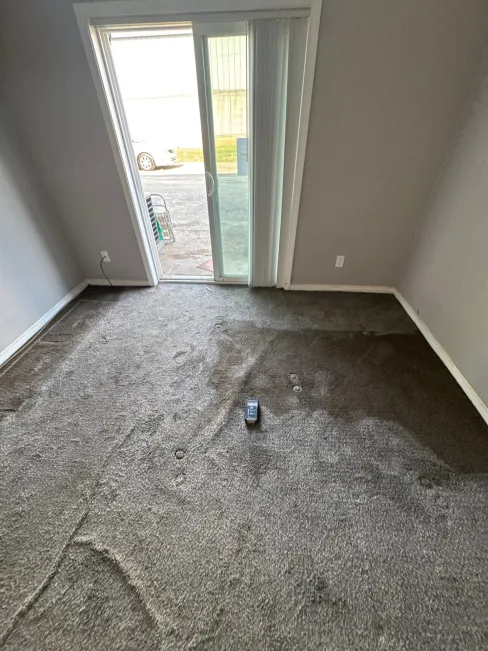 Flood damage inside a ground-floor apartment unit after creek water entered the building