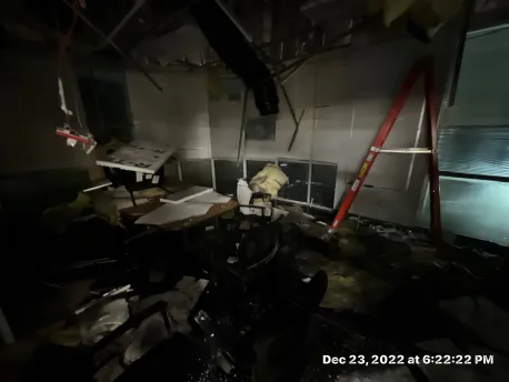 Water spreading across commercial office carpet tile after a fire-suppression line burst in Olathe, Kansas