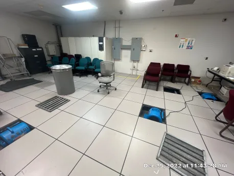 Second raised floor access point with air mover positioned to push heated dehumidified air through the under-floor channel