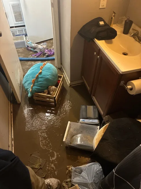 Standing flood water and damaged flooring inside an affected apartment unit