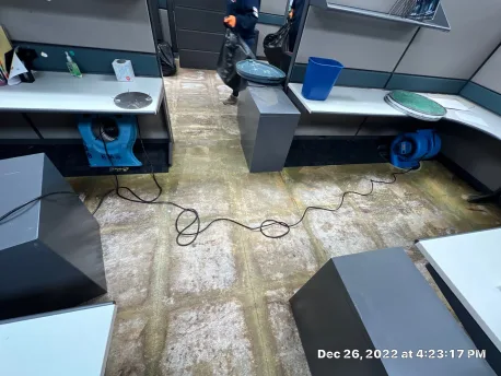Heated dehumidified air directed through an under-floor cable channel to dry a raised access floor in place