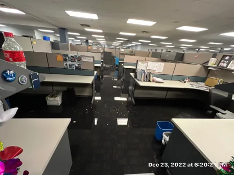 Water spread across raised access office flooring and beneath cubicle runs in the affected department