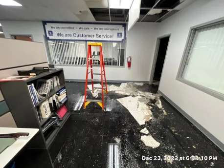 Water damage visible in office drop ceiling tiles below the burst fire-suppression line